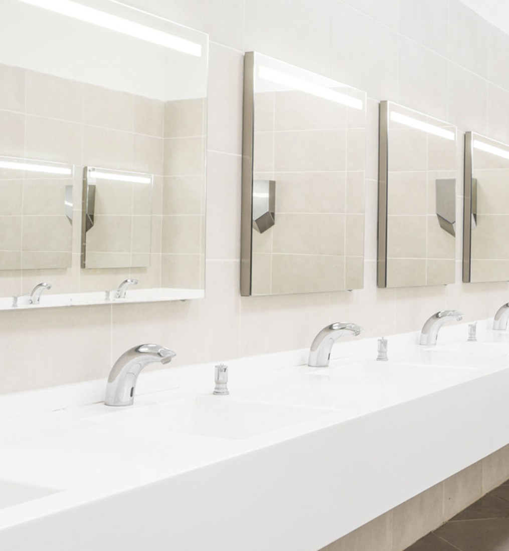 Modern public restroom with white sinks, mirrors, and automatic faucets for an efficient and hygienic experience.