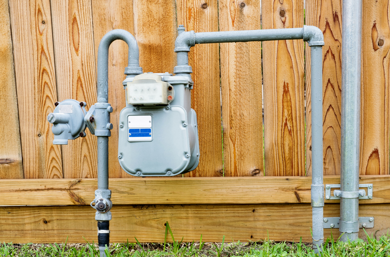 Residential natural gas meter and piping showing the gas shut-off valve location near the home