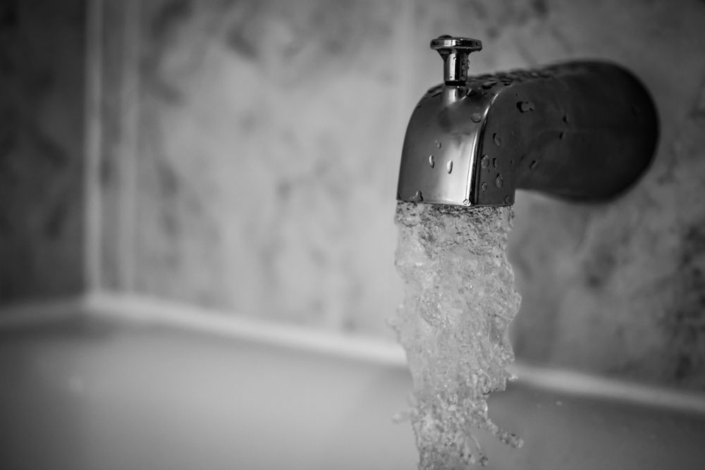 Close-up of a chrome faucet with water flowing in a bathroom setting.