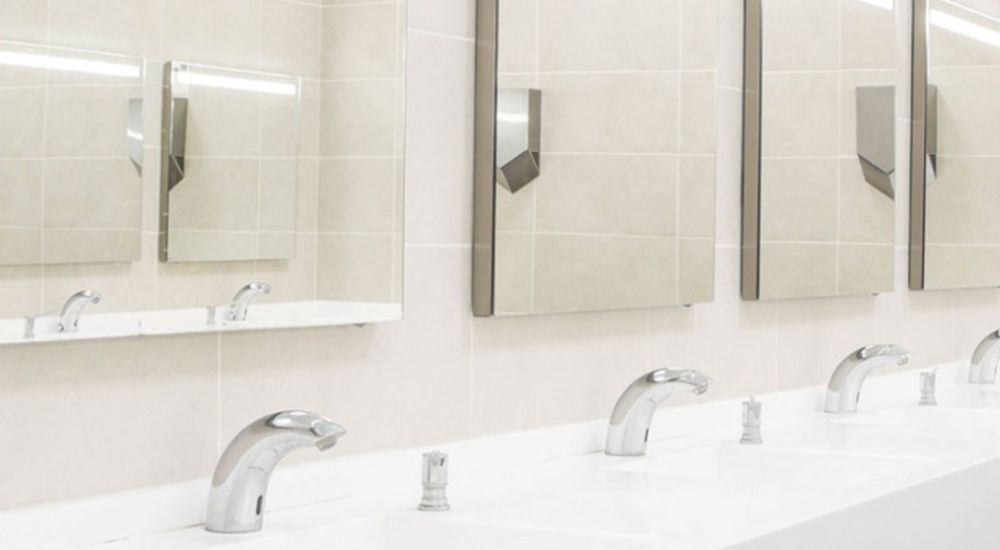 Modern public restroom with white sinks, mirrors, and automatic faucets for an efficient and hygienic experience.