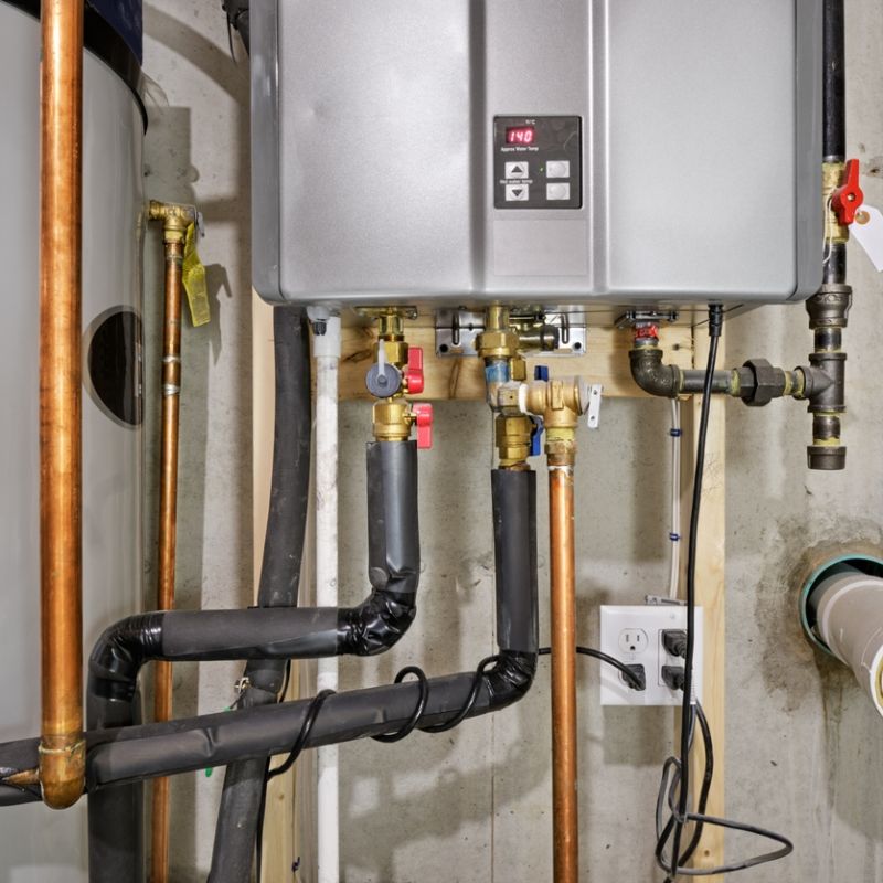 Tankless water heater with copper pipes in a basement, displaying efficient heating system installation.