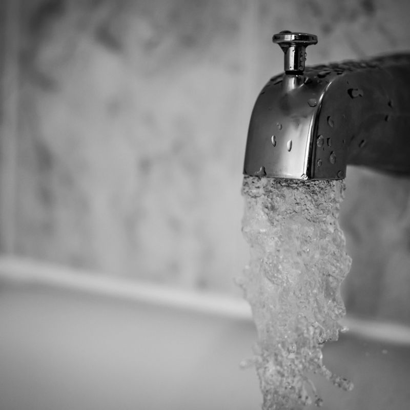 Close-up of a chrome faucet with water flowing in a bathroom setting.