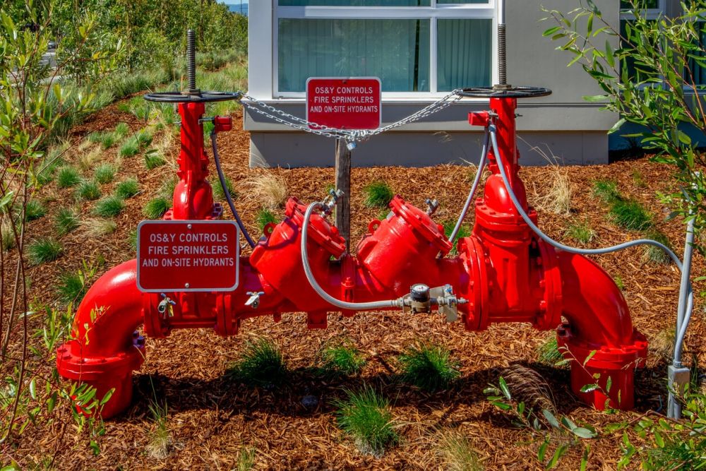 Red OS&Y valve controls connecting fire sprinklers and hydrants outside a building for safety and fire protection.