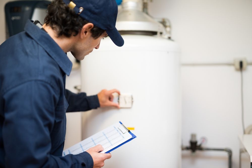 Technician inspecting water heater with clipboard, adjusting settings for efficient home heating maintenance.