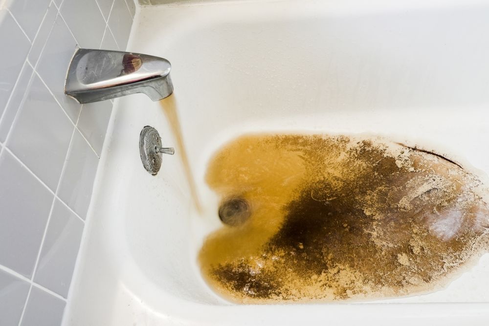 Dirty water filling bathtub, indicating possible plumbing issue or rusty pipes, requiring immediate attention for clean water.