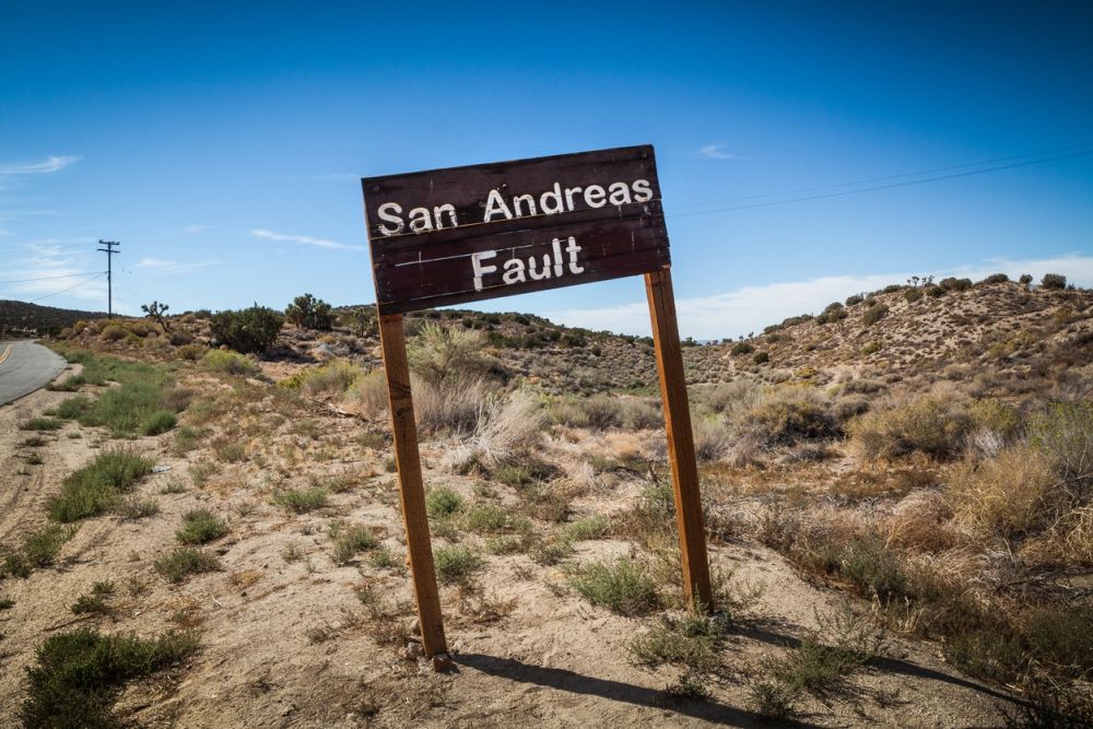 Sign indicating the San Andreas Fault in a desert landscape under a clear blue sky.