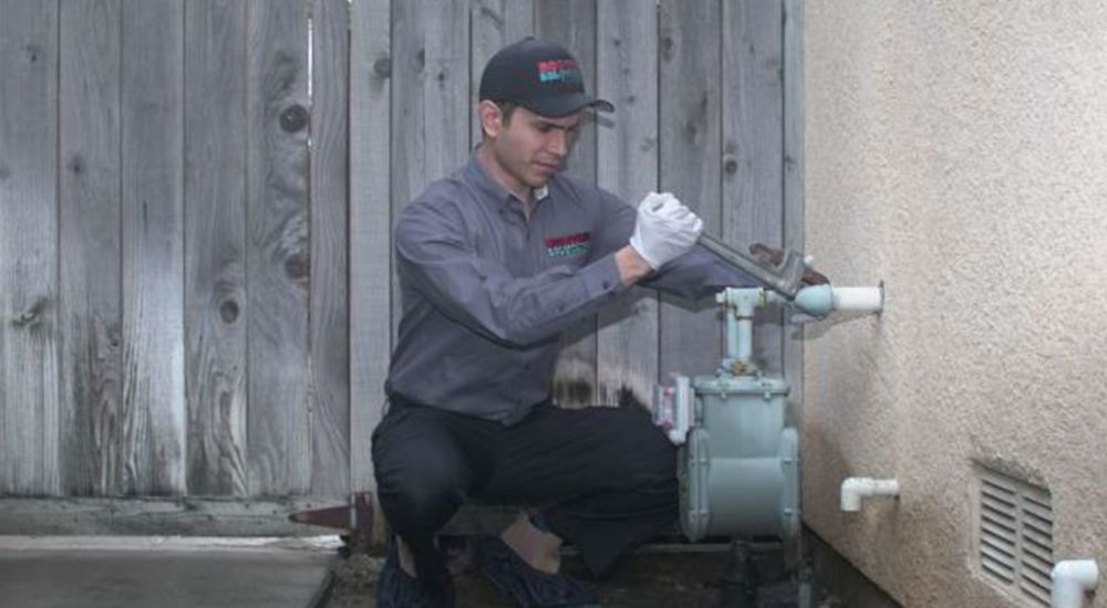 Technician repairs gas meter with wrench outdoors, wearing uniform and cap. Safety and maintenance concept.