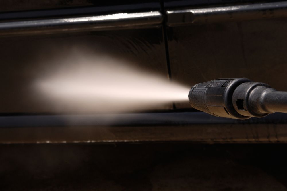 High-pressure water cleaning a surface with power washer for deep cleaning and stain removal.