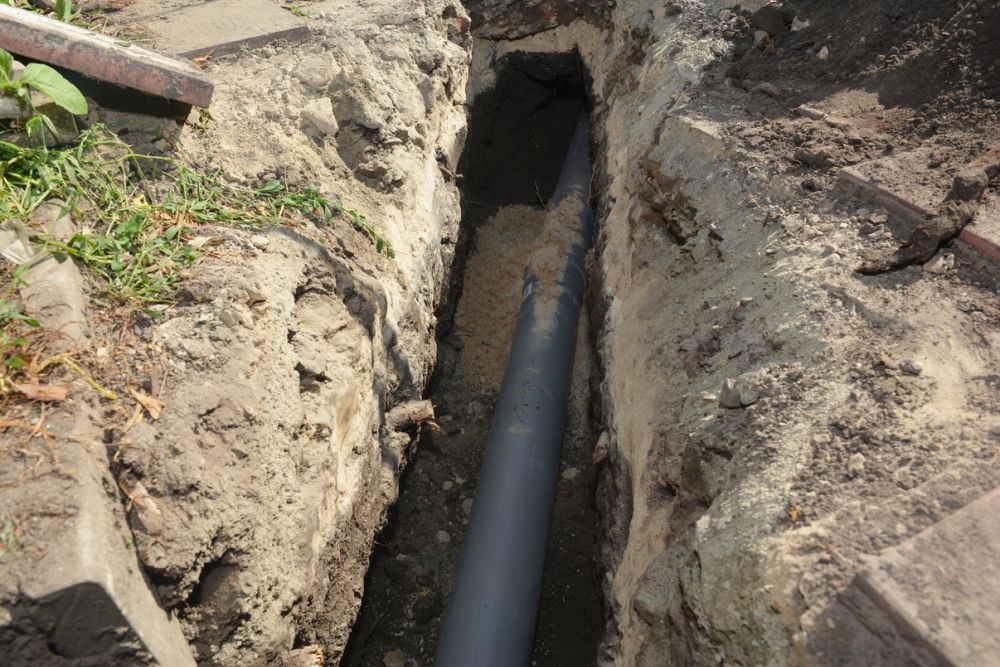 Underground PVC pipe installation in a trench for drainage or plumbing infrastructure.